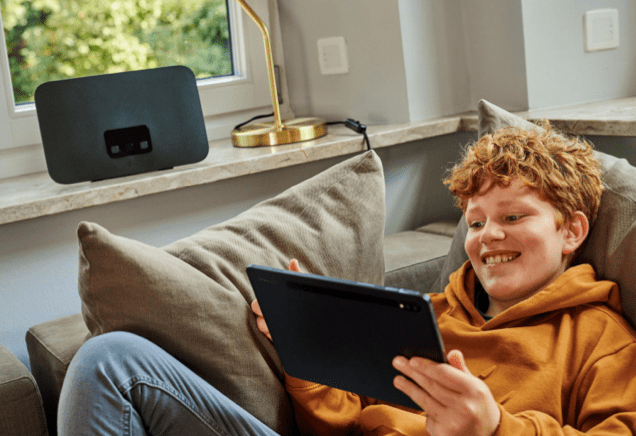 Junge auf der Couch mit Tablet und Router im Hintergrund